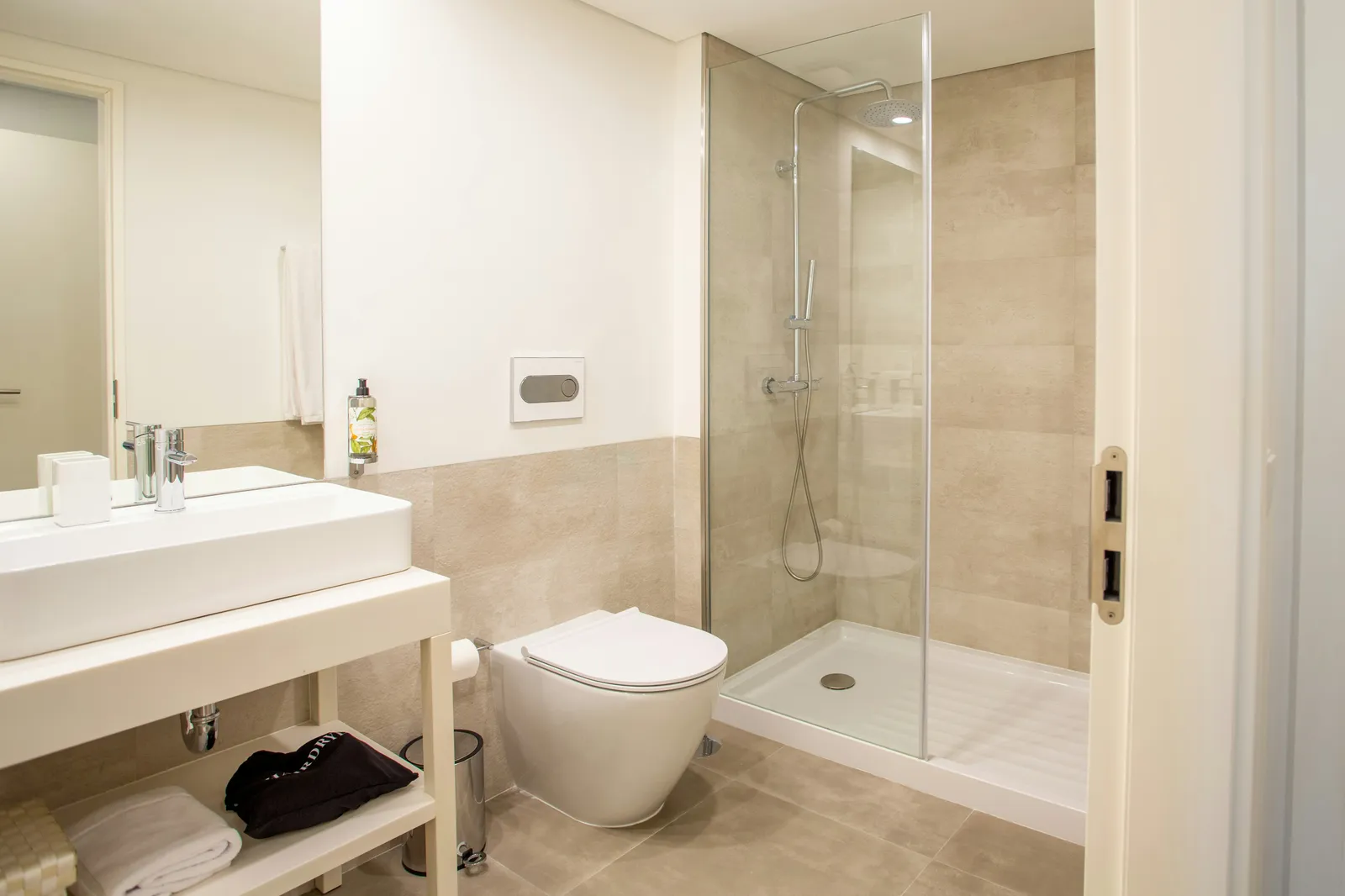 Remodeled bathroom with a glass walk-in shower, floating vanity, and large-format tile